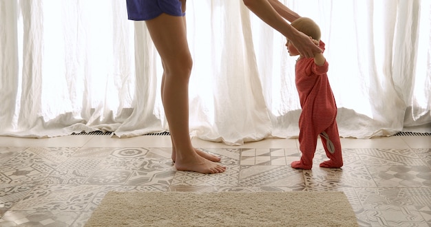 Dziecko stawia pierwsze kroki z pomocą matki