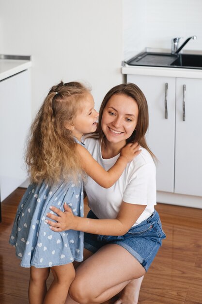 Dziecko szepcze coś do ucha mamy opowiadając sekret