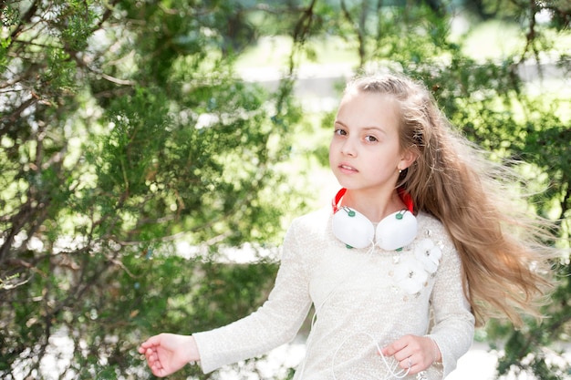 Dziecko tańczy do muzyki w letnim parku Małe dziecko cieszy się muzyką w słuchawkach na świeżym powietrzu Dziewczyna tancerka z długimi rozwianymi włosami Melodia dźwięku i mp3 Letnia zabawa i radość