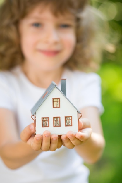 Dziecko trzyma dom w rękach na zewnątrz
