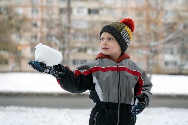 Dziecko Trzyma W Rękach Kawałek śniegu. Chłopiec Grający śnieżkami.