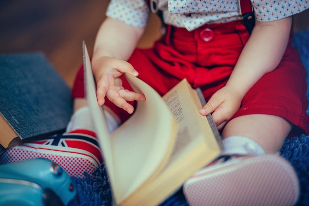 Dziecko trzymające książkę w dłoniach siedzące na podłodze