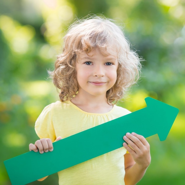 Dziecko trzymające zieloną strzałkę na zewnątrz w parku wiosennym