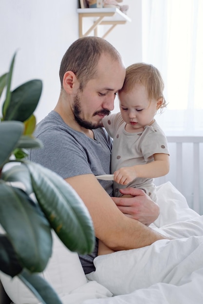 Dziecko trzymane przez ojca, biorąc jego temperaturę, terapia choroba, medycyna koncepcja grypy