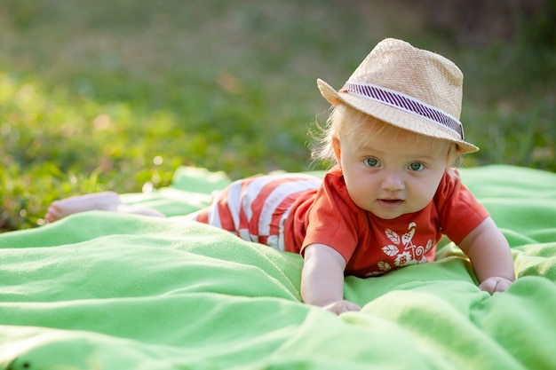 Dziecko w kapeluszu i leżąc na trawie w parku