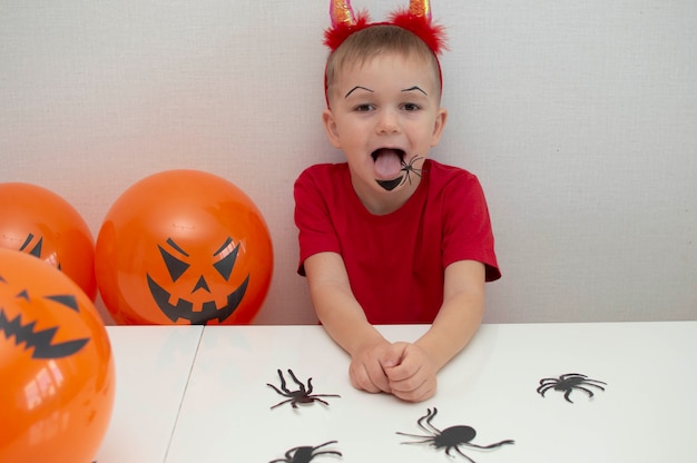 Dziecko w kostiumie trzyma straszne balony na Halloween na białym tle.