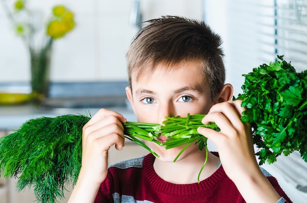 Dziecko w kuchni z ziołami koperkiem i pietruszką, zakrywa twarz jak wąsy