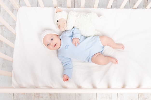 Dziecko w łóżeczku z zabawką pluszowego misia idzie spać lub budzi się rano, koncepcja rodziny i narodzin