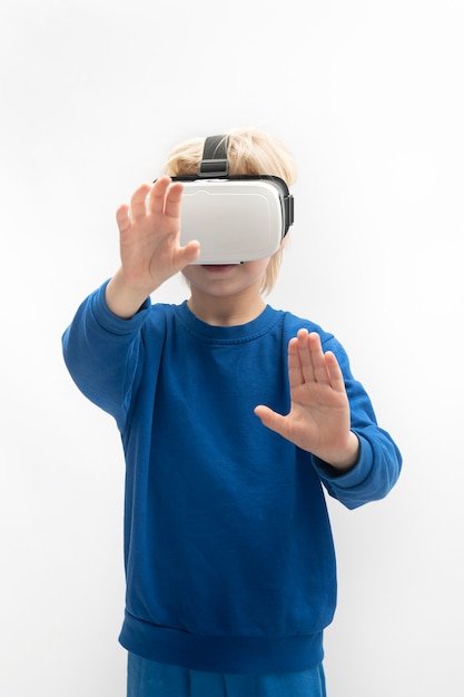 Dziecko w okularach VR gra w wirtualną rzeczywistość. Na białym tle na białej powierzchni. Rama pionowa.