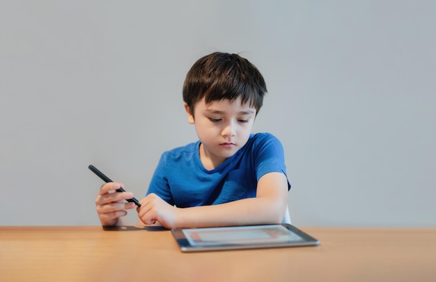 Dziecko w szkole uczy się w klasie online w domu Dziecko używa tabletu do odrabiania lekcji Młody chłopiec studiuje rozmowę wideo online Koncepcja edukacji e-learningowej lub nauczania w domu