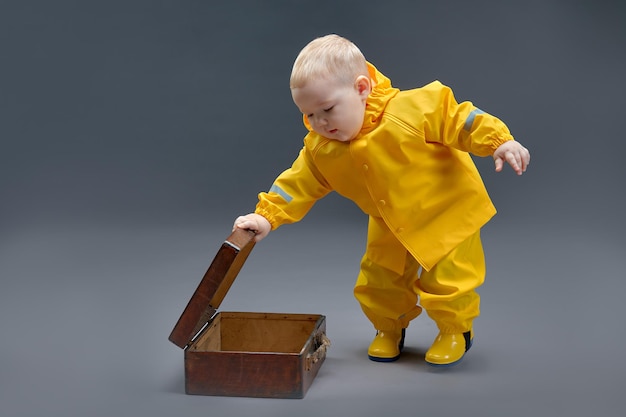 Dziecko w żółtym kombinezonie ochronnym otwiera pudełko