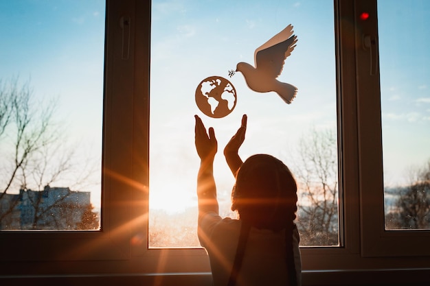 Dziecko wyciąga ręce światło słoneczne za oknem latający świat gołębi z gałęziami wymusza koncepcję kuli ziemskiej pokój świat bez wojny ekologia