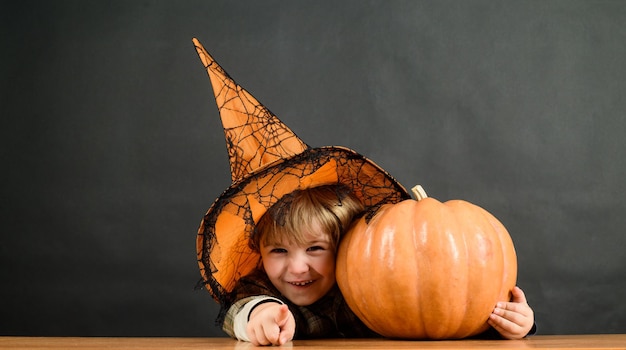 Dziecko z dynią szczęśliwego halloween impreza z okazji halloween mały chłopiec w kapeluszu wiedźmy z dynią halloween