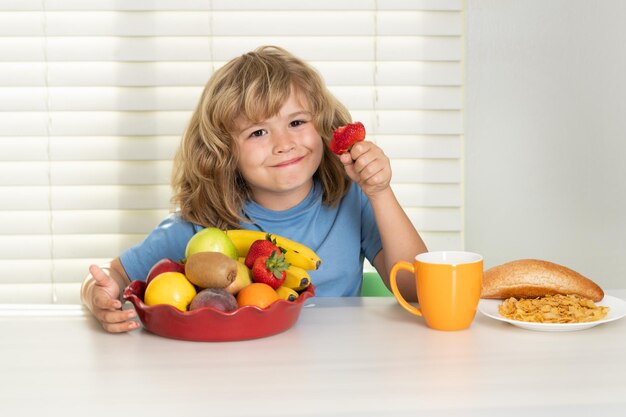 Dziecko z truskawkowymi letnimi owocami chłopiec jedzący zdrową żywność warzywa śniadanie z owocami mleka