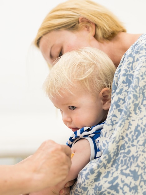 Zdjęcie dziecko zaszczepione przez pediatrę w obecności matki przeciwko szczepieniu zapobiegawczemu