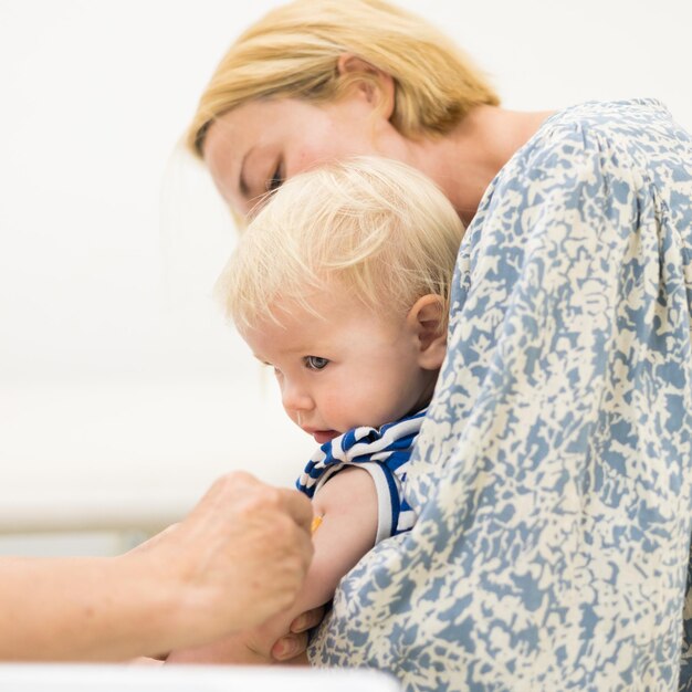 Dziecko zaszczepione przez pediatrę w obecności matki, szczepienie profilaktyczne przeciw zaparciom