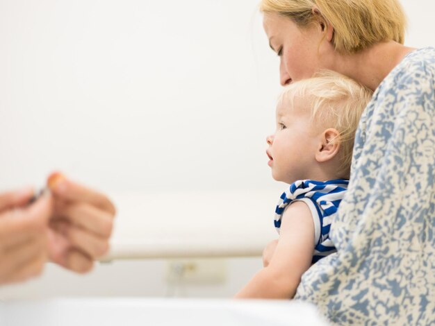 Dziecko zaszczepione przez pediatrę w obecności matki, szczepienie profilaktyczne przeciw zaparciom