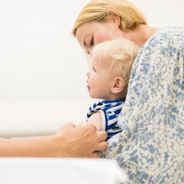 Dziecko zaszczepione przez pediatrę w obecności matki, szczepienie profilaktyczne przeciw zaparciom