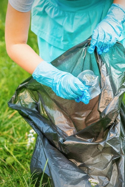 Dziecko Zbiera Plastikowe śmieci Z Trawy Wyrzucając śmieci Do Worka Na śmieci W Parku