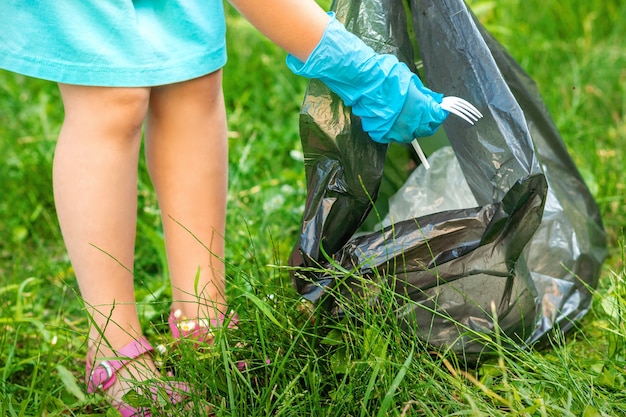 Dziecko Zbiera Plastikowe śmieci Z Trawy Wyrzucając śmieci Do Worka Na śmieci W Parku