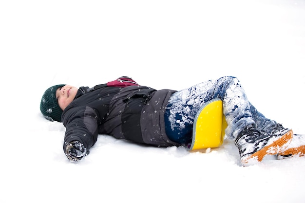 Dziecko zimą Chłopiec upadł na sanki i leży w śniegu