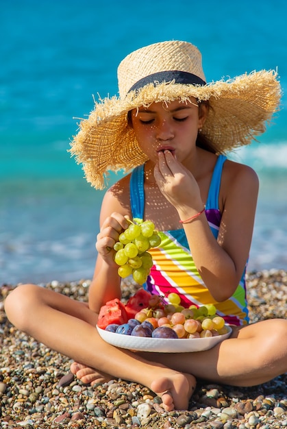 Dziecko zjada owoce nad morzem. Selektywne skupienie.
