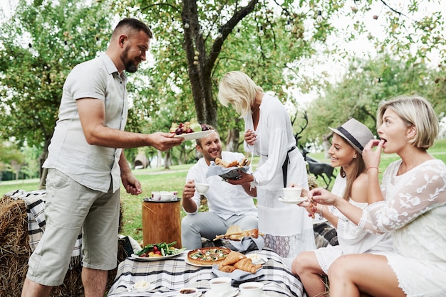 Dzielenie Się Deserami. Grupa Dorosłych Przyjaciół Odpoczywa I Rozmawia Na Podwórku Restauracji W Porze Kolacji.