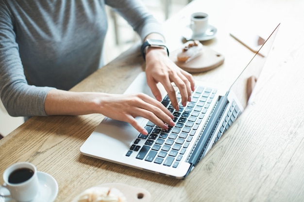 Dzień w kawiarni. Zamknij się młoda kobieta w kawiarni. Student o pyszny napój kawowy. Używa laptopa