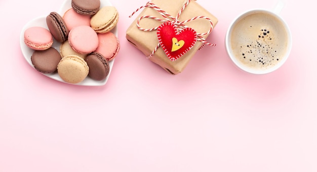 Dzień Walentynek z makaronami na płytce w kształcie serca kawa i pudełko z prezentami na różowym tle