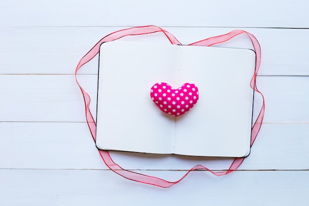Zdjęcie dzienniczka notatnik z valentine sercami na białym drewnianym tle.