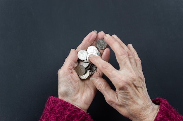 Dziesięciorublowe monety wlewają się w ręce emeryta, pojęcie ubóstwa