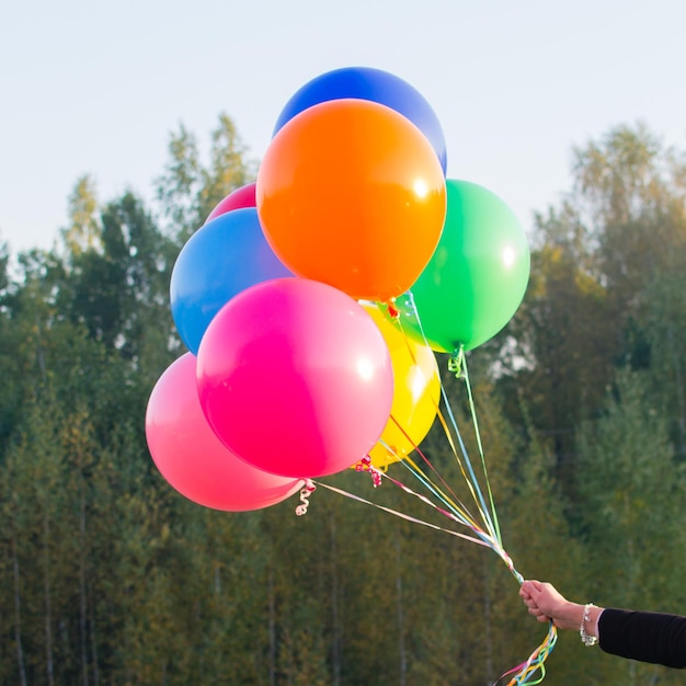 Dziewczęca ręka trzyma wielokolorowe balony z helem