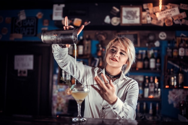 Dziewczyna barmanka formułuje koktajl w restauracji brasserie