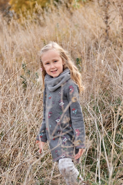 Dziewczyna bawi się w suchym trzcinowym polu jesienny rodzinny spacer w lesie