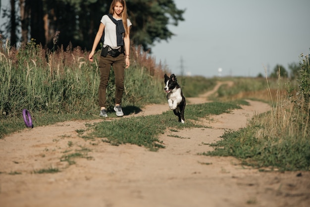 Dziewczyna bawi się z czarno-białym border collie szczeniak na leśnej ścieżce