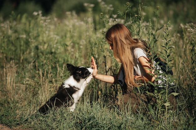 Zdjęcie dziewczyna bawi się z czarno-białym border collie szczeniak na leśnej ścieżce