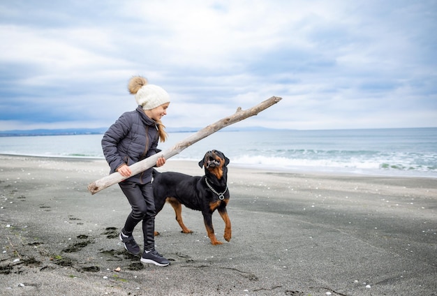 Dziewczyna Bawi Się Z Psem Rottweilera W Chłodne Dni Na Plaży