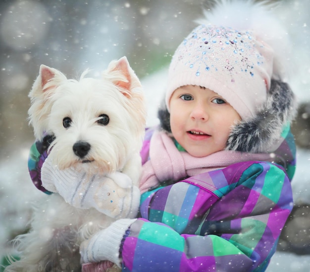 Dziewczyna bawiąca się z białym psem zimowy śnieg szczęście