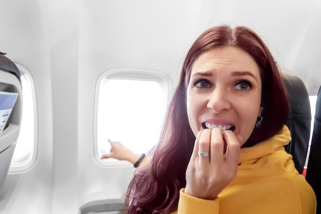 Zdjęcie dziewczyna boi się latać samolotem. płukanie, gryzie palce. pojęcie podróży, lotu, strachu.
