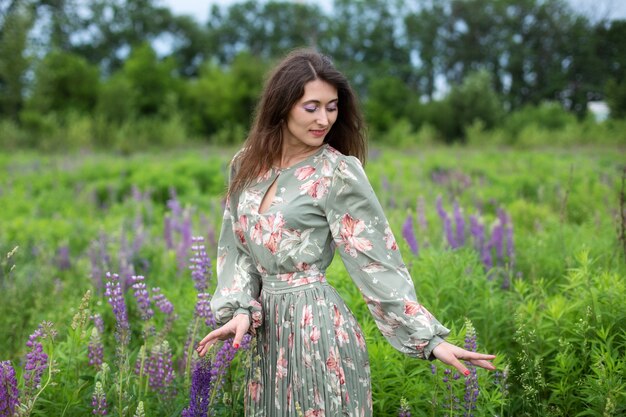 dziewczyna chodząca po polu lato z polne kwiaty kobieta w sukience w kwitnącym polu łubinu