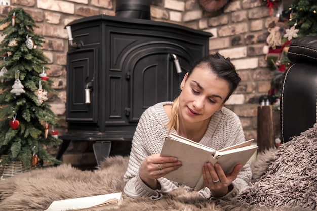 dziewczyna czyta książkę w przytulnej domowej atmosferze przy kominku