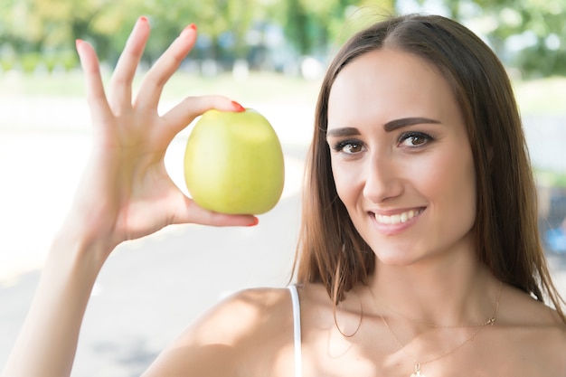 Dziewczyna dieta słoneczny odkryty. Sport i zdrowie. Kobieta trzyma zielone jabłko. Aktywność letnia i energia. owoce i witaminy.