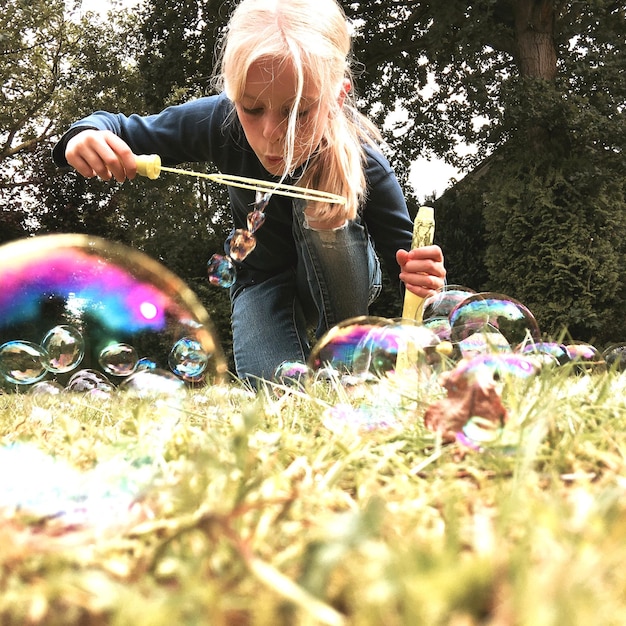 Zdjęcie dziewczyna dmuchająca bąbelkami z różdżki w parku