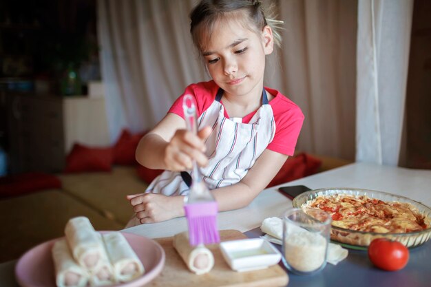 Dziewczyna gotuje kiełbasę zwijaną w cieście filo na śniadanie mały szef kuchni lubi smaczną przekąskę