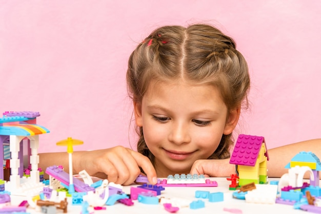 Dziewczyna gra konstruktora na różowej powierzchni