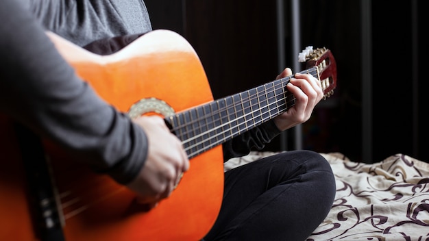 Dziewczyna gra na akustycznym sześciostrunowym gitarze z bliska. lekcje instrumentów muzycznych.