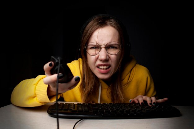 Dziewczyna-gracz siedzi przy laptopie w nocy w domu, studentka gra w gry, które przegrywa i wygrywa