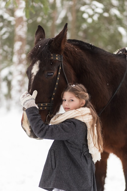dziewczyna i brązowy koń w zimie w przyrodzie