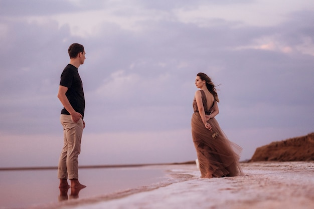 Dziewczyna i facet na brzegu różowego słonego jeziora o zachodzie słońca