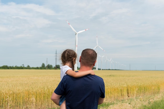 Dziewczyna i jej tata patrzą na generator wiatrowy w polu Ekologia Przyszłość